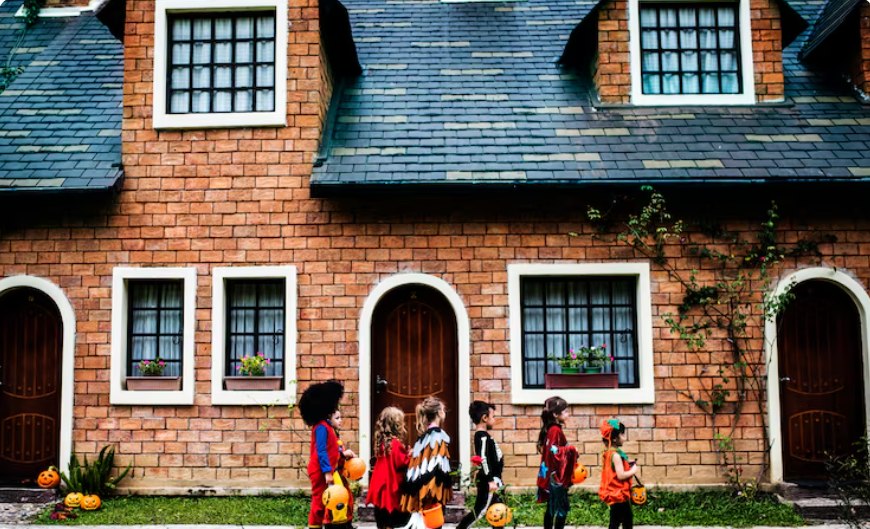 Children in costumes walking past a brick schoolhouse