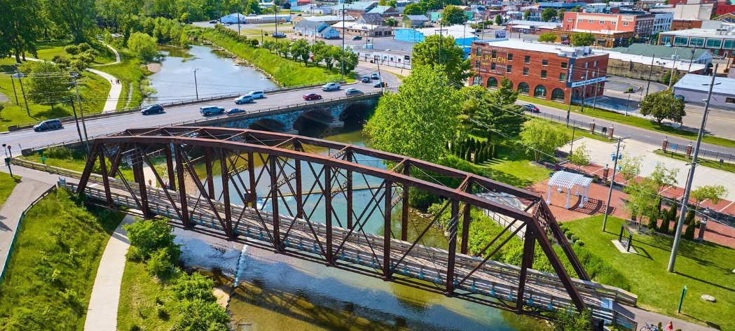 An aerial view of a town with a river and a steel bridge